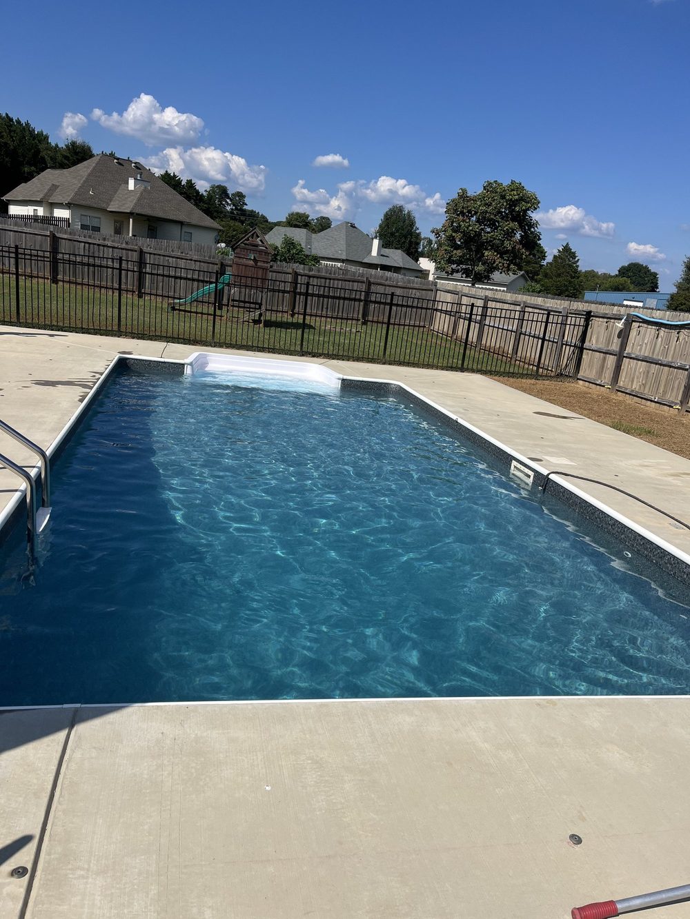 Clear fenced-in backyard pool serviced by Alabama Aquatics