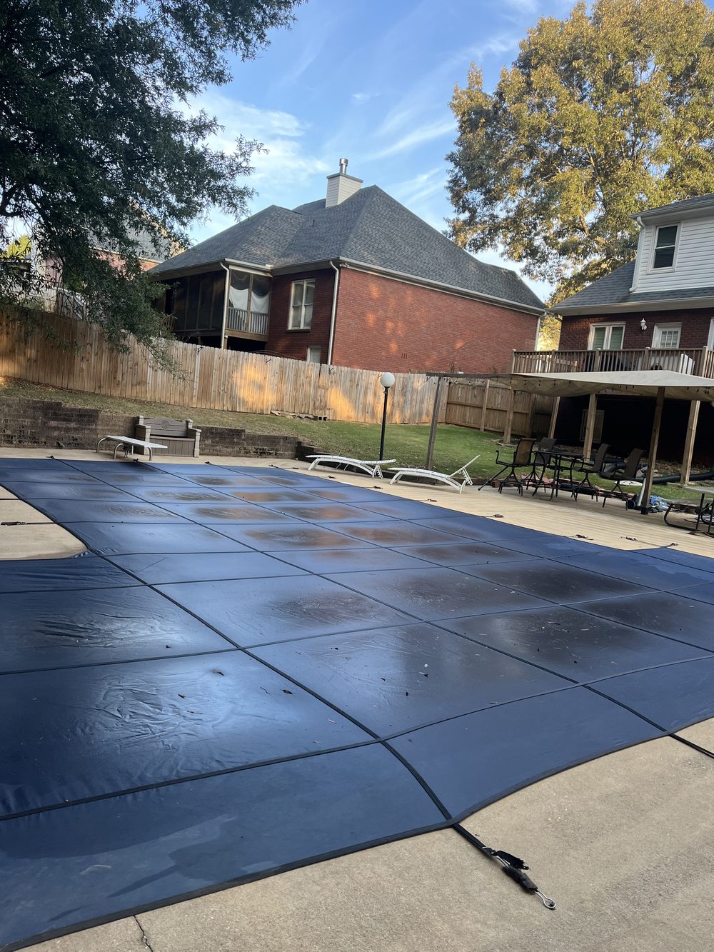 Pool covered for the season behind a brick home