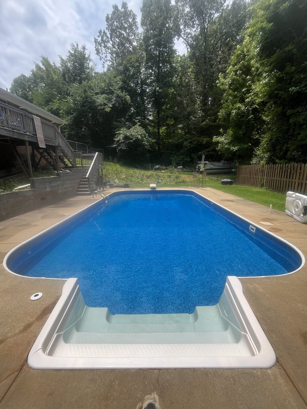 Clear vinyl liner pool with built-in steps on a wooded lot